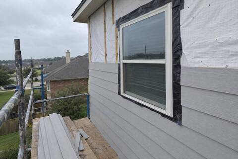 Fiber-cement lap plank going up on a two-story wall