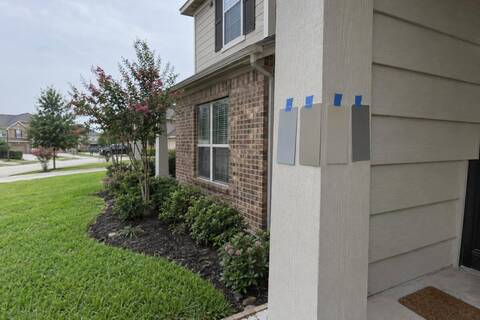 Paint swatches taped to a porch post on a brick-and-siding two-story elevation