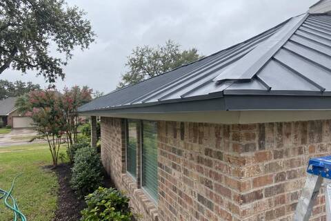 Standing seam metal panels on a brick-veneer house